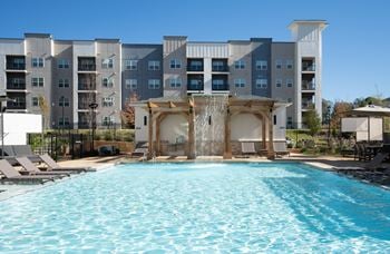 A large swimming pool in front of a multi-story apartment building at The Delaney at East Park Apartments, Georgia